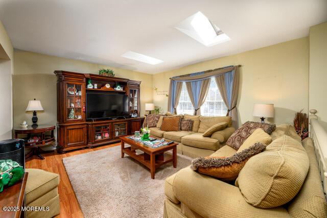 living area with a skylight and wood finished floors