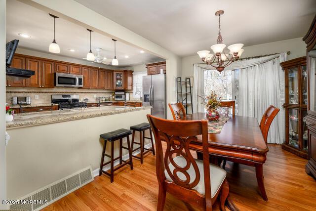 dining area featuring a chandelier, visible vents, and light wood-style flooring