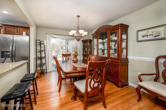 dining space featuring light wood-style floors, baseboards, and a chandelier