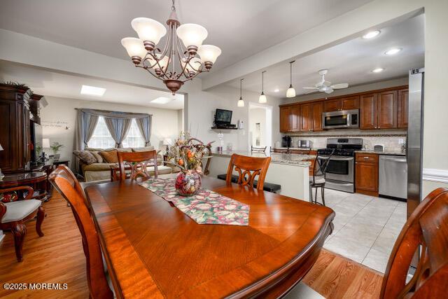 dining room with ceiling fan with notable chandelier, light wood-style flooring, and recessed lighting