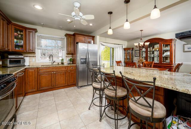 kitchen with appliances with stainless steel finishes, a kitchen bar, a sink, and light stone countertops