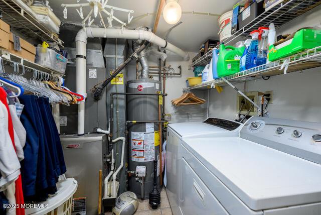 laundry area featuring laundry area, water heater, light tile patterned floors, and washing machine and clothes dryer