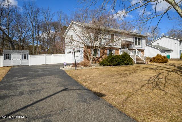 view of front of property with a garage, an outbuilding, fence, a shed, and brick siding