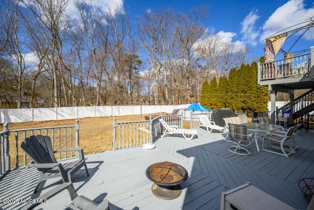 wooden deck featuring fence, a fire pit, and outdoor dining space