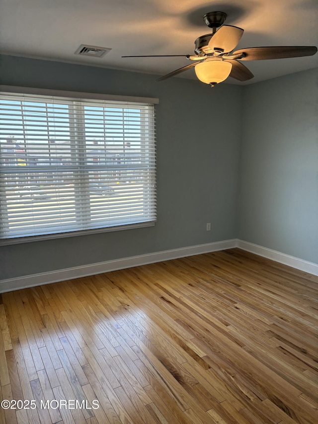 empty room with visible vents, ceiling fan, baseboards, and wood finished floors