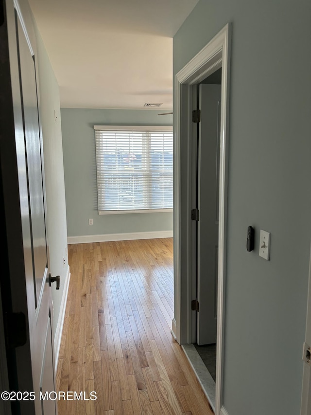 hallway featuring wood finished floors, visible vents, and baseboards