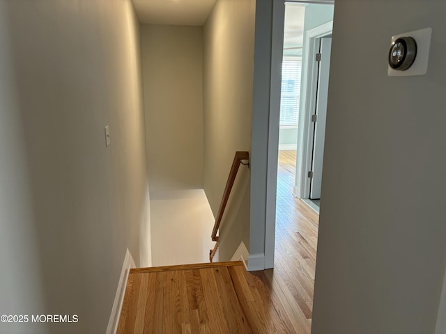 corridor featuring wood finished floors, an upstairs landing, and baseboards