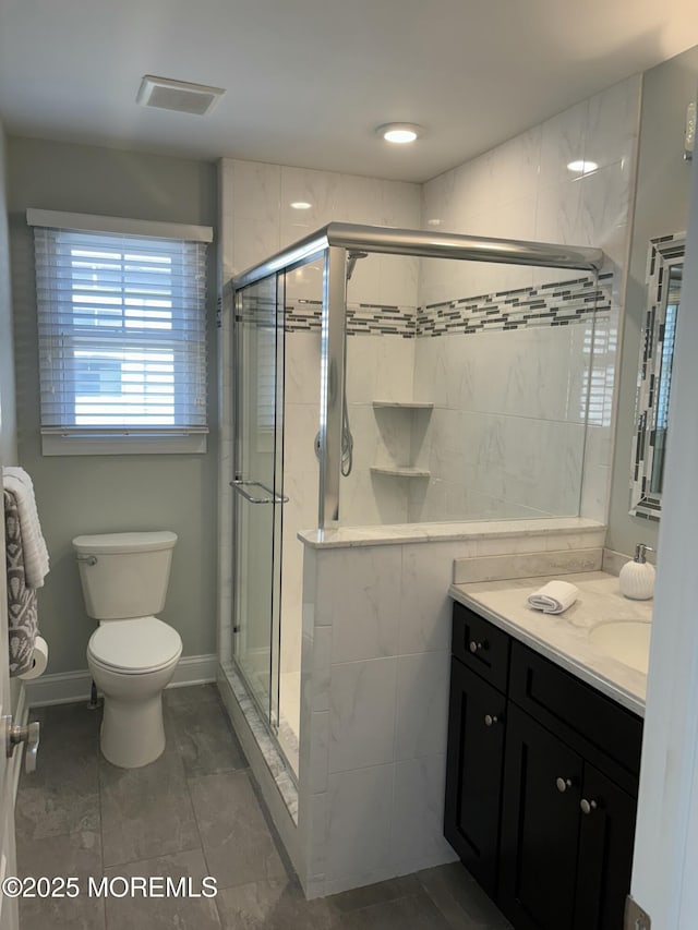 bathroom with vanity, toilet, baseboards, and a stall shower