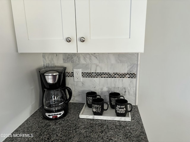 room details featuring tasteful backsplash, white cabinetry, and dark stone counters