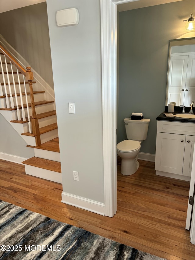 bathroom featuring toilet, vanity, baseboards, and wood finished floors