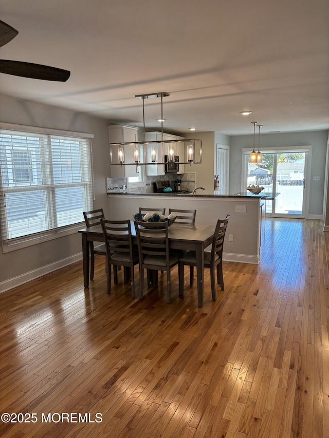 dining area with light wood-type flooring, baseboards, and an inviting chandelier