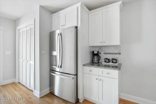 kitchen with white cabinets, backsplash, stainless steel fridge with ice dispenser, and light stone countertops