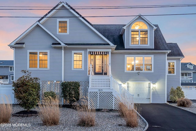 view of front of property with driveway, an attached garage, and fence