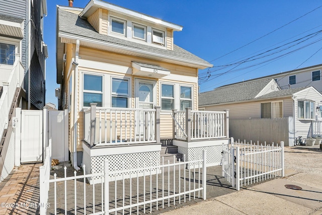 view of front of property featuring a gate, fence, and roof with shingles