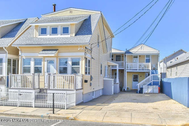 view of front of house with a shingled roof and fence