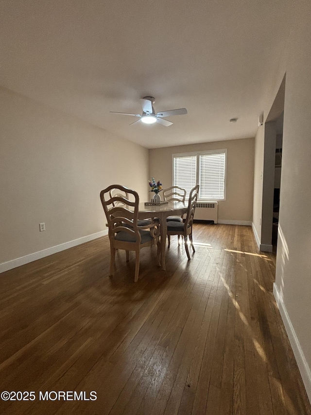 dining space with baseboards, dark wood finished floors, radiator heating unit, and ceiling fan