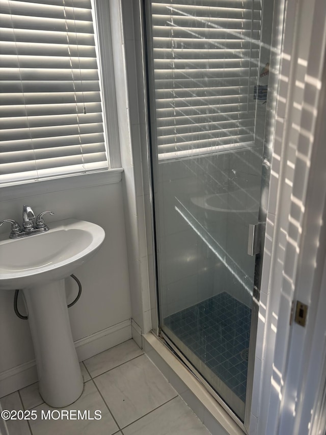 bathroom featuring a stall shower, baseboards, and a sink