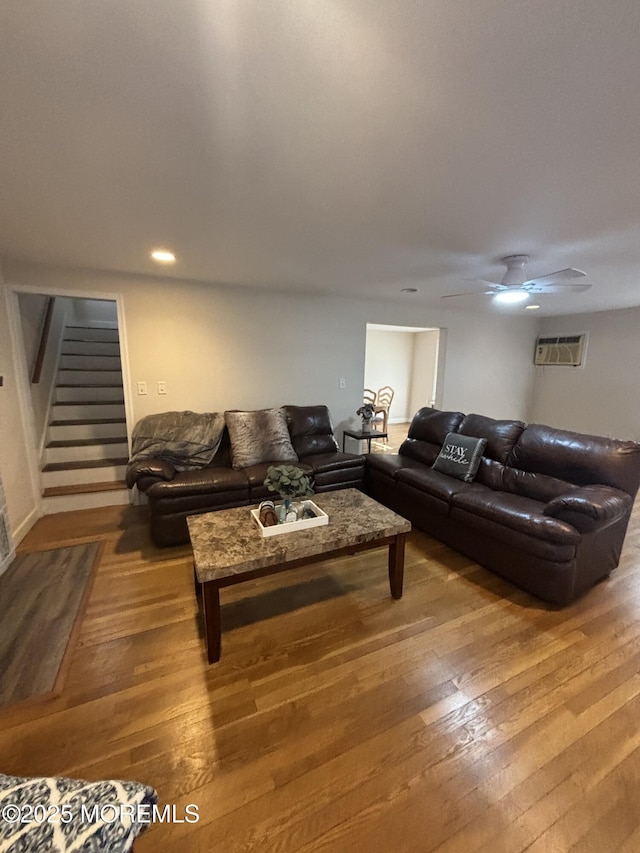 living room featuring hardwood / wood-style flooring, stairway, a ceiling fan, and a wall mounted air conditioner