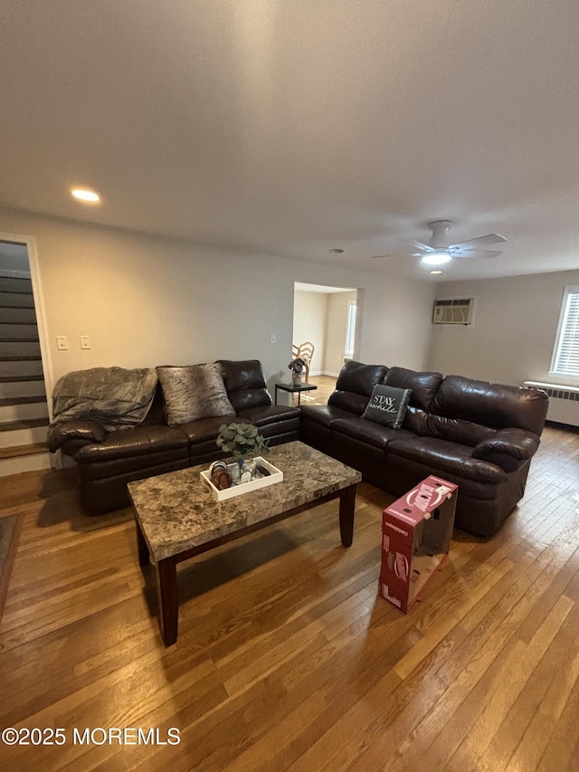 living room featuring radiator, a wall mounted air conditioner, ceiling fan, and wood-type flooring