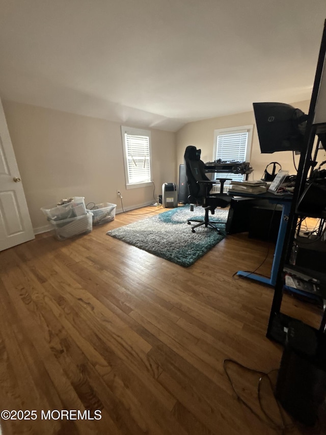 office space featuring lofted ceiling, baseboards, and wood finished floors