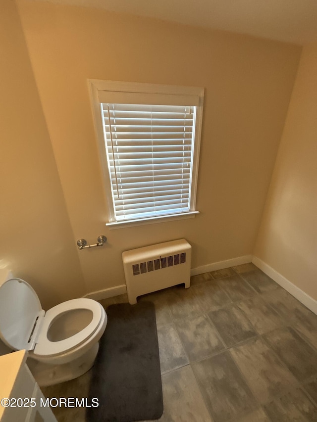 bathroom with radiator, baseboards, and toilet