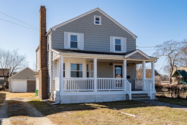 view of front of house featuring a porch, an outbuilding, a front yard, and a detached garage