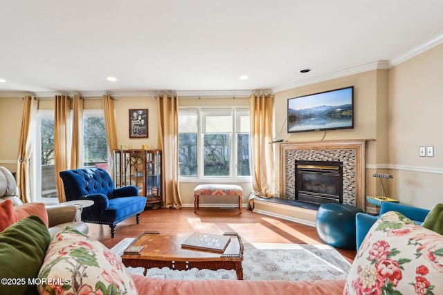 living room with recessed lighting, crown molding, a tiled fireplace, and wood finished floors