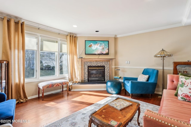 living area with baseboards, a fireplace, ornamental molding, and wood finished floors