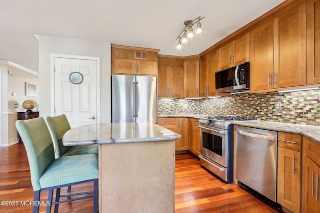 kitchen featuring a breakfast bar area, visible vents, appliances with stainless steel finishes, light wood-type flooring, and decorative backsplash