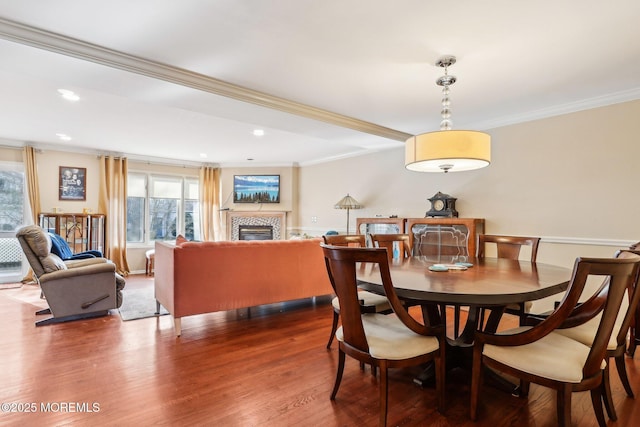 dining area with dark wood-style floors, ornamental molding, a tile fireplace, and recessed lighting