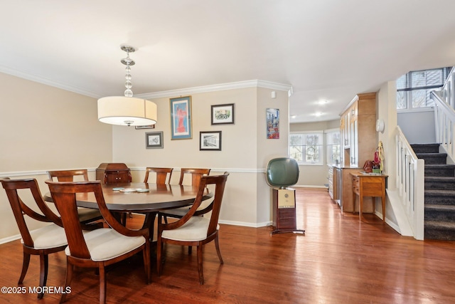 dining space with ornamental molding, wood finished floors, baseboards, and stairs