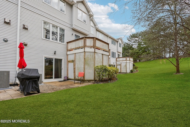 rear view of property with cooling unit, a lawn, and a patio