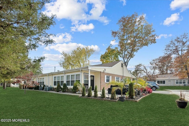 view of front of home featuring a front yard, brick siding, and central AC unit