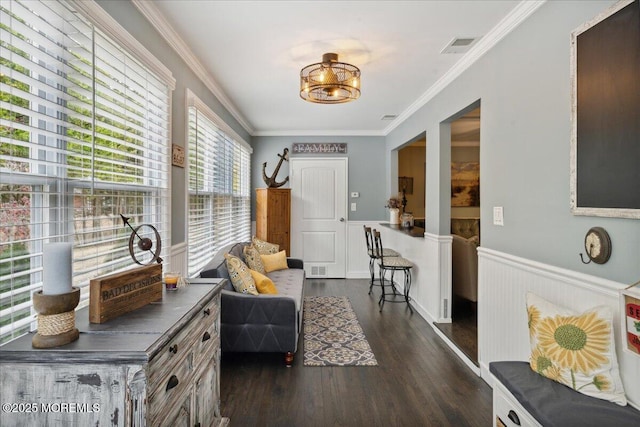 sitting room with a wainscoted wall, dark wood-style floors, visible vents, and crown molding