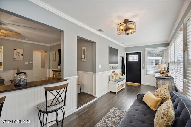 entryway with ceiling fan, dark wood-type flooring, wainscoting, and crown molding