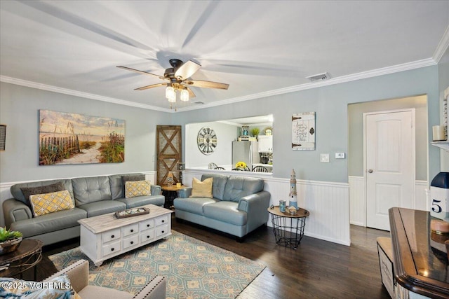 living room featuring crown molding, visible vents, a ceiling fan, wainscoting, and wood finished floors