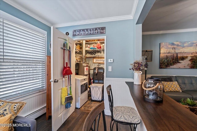 dining area with a baseboard heating unit, wood finished floors, ornamental molding, wainscoting, and washer / dryer