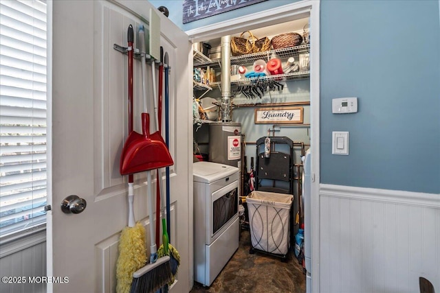 laundry room featuring laundry area, water heater, a wainscoted wall, and washer / dryer