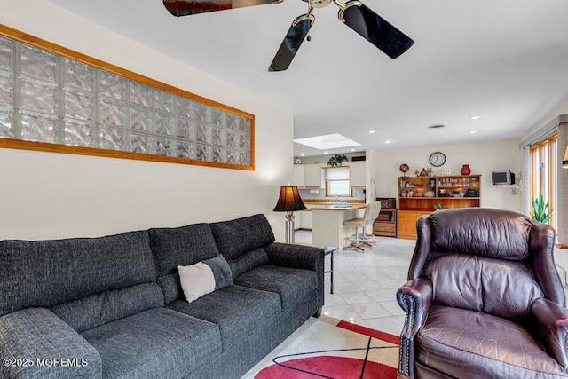 living area with light tile patterned floors, a skylight, a ceiling fan, and recessed lighting