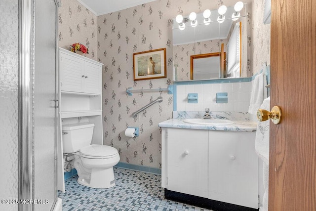 full bath with toilet, vanity, baseboards, a stall shower, and wallpapered walls