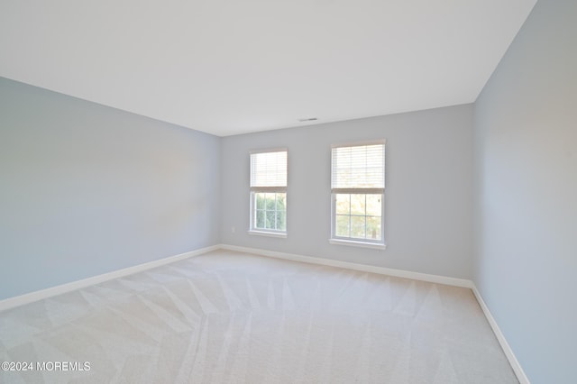 empty room featuring light carpet, visible vents, and baseboards