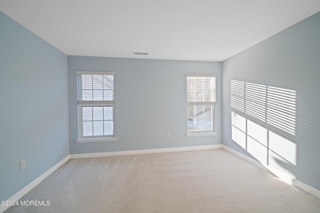 carpeted spare room featuring visible vents and baseboards