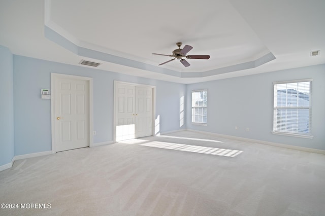 spare room featuring light carpet, visible vents, and a raised ceiling