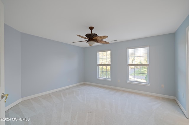 spare room featuring light carpet, a ceiling fan, visible vents, and baseboards