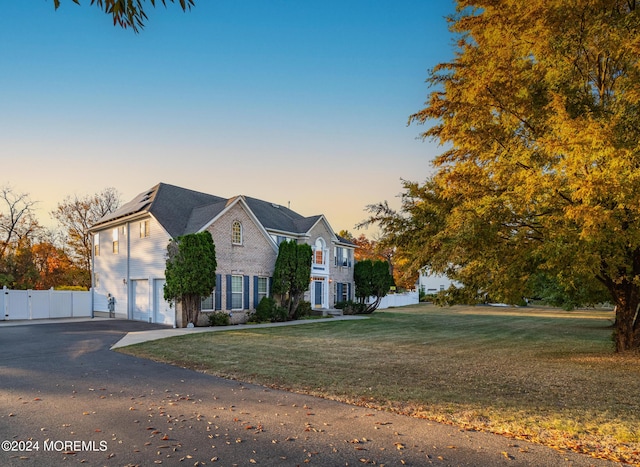 traditional home with driveway, a lawn, an attached garage, and fence