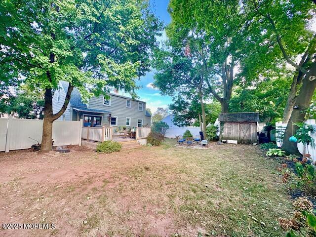 view of yard featuring a deck, a shed, an outdoor structure, and a fenced backyard