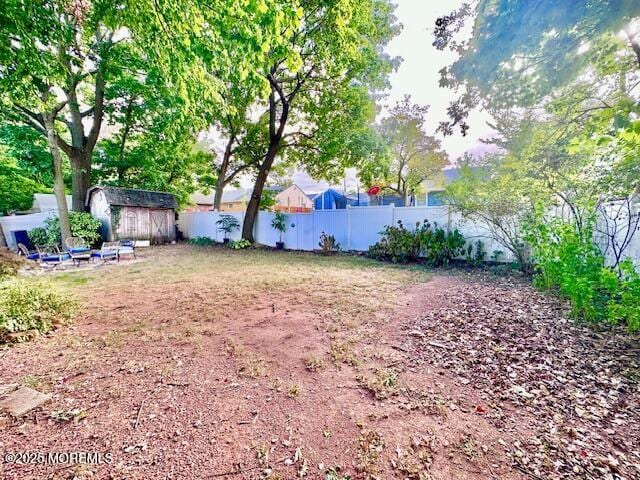 view of yard with a shed, a fenced backyard, and an outbuilding