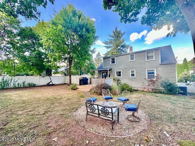 rear view of property featuring a deck, a lawn, and fence