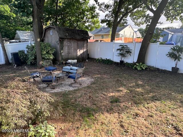 view of yard with an outbuilding, a shed, a fire pit, and a fenced backyard