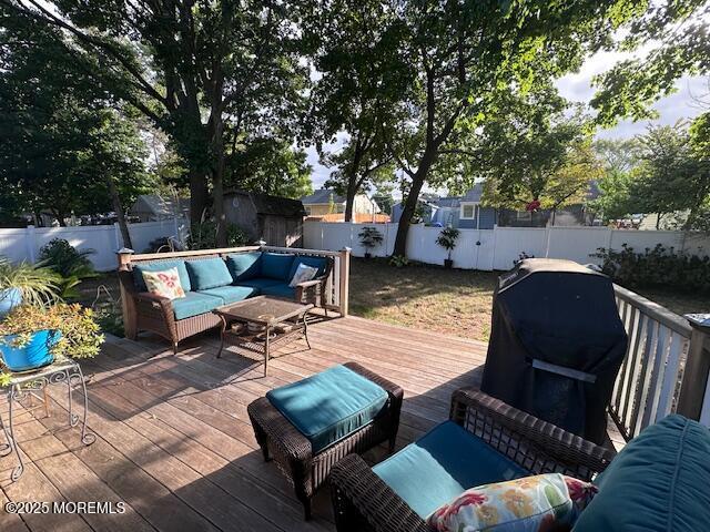 wooden deck featuring a fenced backyard, a grill, an outdoor hangout area, and an outdoor structure